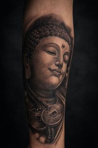 Tatuaje realista de Buda en antebrazo